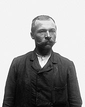Portrait en noir et blanc d'un homme dégarni portant des moustaches.