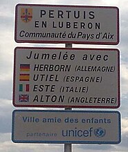 Panneau d'entrée de ville affichant les jumelages et partenariats de Pertuis en Luberon en 2009.