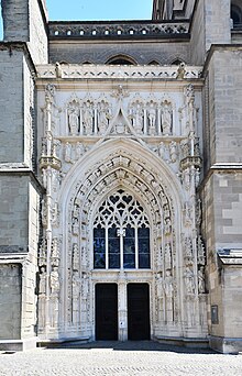 Grand Portail, ou portail de Montfalcon, entièrement restauré en 1892-1909. Porte principale à double battant avec trumeau à niche vide, créé à cette époque.