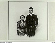 Photo en noir et blanc d'un homme debout en uniforme et d'une femme, assise.