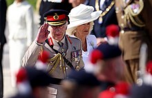 Charles, in military uniform, waves at the crowd.