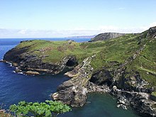 Vue aérienne de falaises côtières dans lesquelles se distingue l'entrée d'une grotte.