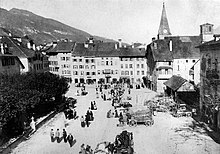 Photo noire et blanche d'une place entourée de bâtiments.