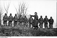 Franco-atiradores da Wehrmacht recebendo instruções em campo de treinamento, em seus uniformes de camuflagem. Alemanha Nazista, 1943.