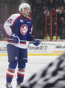 Photographie d'un joueur de hockey sur glace avec un uniforme bleu, blanc et rouge.