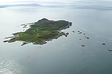 A green island sits in a clam sea. There are numerous small islets in the surrounding waters.