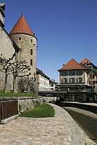 photographie en couleurs d'une partie des douves d'un château, de son enceinte et d'une des tours qui la flanquent.