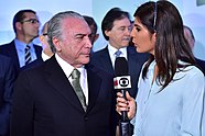 Uma repórter de televisão, Andréia Sadi, em entrevista com o então presidente do Brasil Michel Temer.