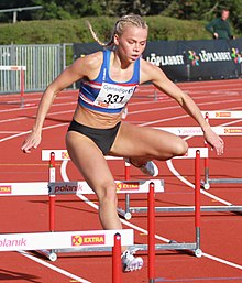 A woman clears a hurdle on a 400 metre track