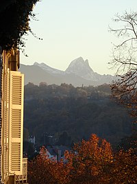 Photographie en couleurs de montagnes enneigées à l'horizon d'une forêt en automne.