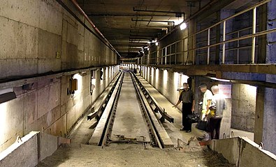 View of a track from a sandpile, in the Montreal Metro near the Beaugrand Station, showing the inverted L cross-section of the guide bars (the extreme flared ends are a fabricated inverse U), precast concrete roll ways and conventional track