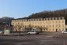 Vue panoramique de trois bâtiments formant les côtés d'un carré avec en son centre un parking.