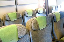 Kabin ekonomi premium pada sebuah pesawat terbang. Rows of seats arranged between aisles.