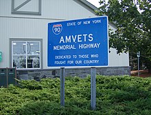 A blue sign with the I-90 sign and "AMVETS Memorial Highway"