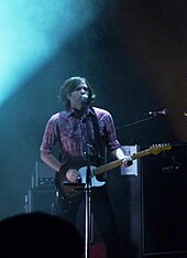 photo d'un homme jouant de la guitare et chantant sur scène.