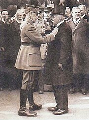 Photo noir et blanc du maréchal Foch remettant la médaille de chevalier de la Légion d'honneur à Paul Michaux devant la foule.