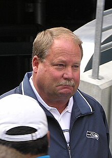 Candid head and shoulders photograph of Holmgren wearing a green jacket over a white shirt
