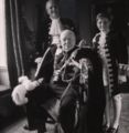 Photograph shows Winston Churchill, full-length portrait, seated, facing front, with his son and grandson standing behind him, wearing coronation robes (Churchill, Winston, Sir, 1874-1965--Family. Churchill, Randolph Spencer, 1911-1968. Churchill, Winston Spencer, 1940-2010)