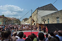 Photographie d'un spectacle en plein-air entouré d'une foule.