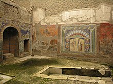 mur au fondcouvert de mosaïques colorés, à gauche niche arrondie. Devant, une grande banquette en U