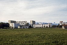 photographie en couleurs de barres d'immeubles an arrière-plan d'un terrain engazonné.