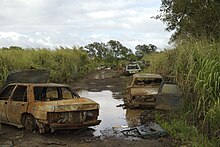 mudy road blocked by car hulks