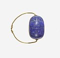 Prstni prstan staroegipčanskega skarabeja; 1850–1750 pr. skarabej lapis lazuli, postavljen v zlato ploščo in na zlati žični prstan lapis-lazuli; premer: 2,5 cm, skarabej: 1,8 cm; Metropolitanski muzej umetnosti