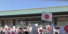 Um grupo de pessoas exibindo bandeiras do Japão em um palácio.