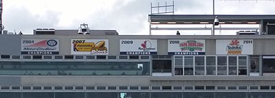 Five banners in a row at the top of the stadium press box with dates and logos for each bowl game, presented in chronological order from left to right