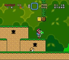 Esta captura de tela mostra Mario monta em Yoshi durante a primeira fase do jogo. O cenário mostra um ambiente de selva com blocos flutuantes espalhados pelo ar. A interface exibida nos cantos mostra o número de vidas que o jogador tem, as Dragon Coins coletadas, o power-up armazenado do jogador, o tempo restante da fase, o número de moedas e pontuação total do jogador.