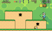 Esta captura de tela mostra Luigi montando Yoshi durante um dos estágios iniciais do jogo na versão de Game Boy Advance. O cenário mostra um ambiente de selva com blocos flutuantes espalhados pelo ar. A interface exibida na parte superior da imagem mostra o número de vidas, multiplicador de pontos, item especial, tempo restante, número de moedas e pontuação total.