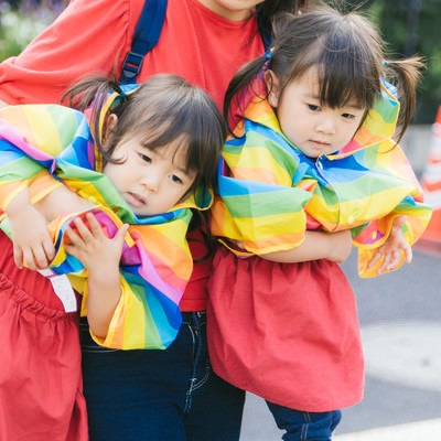 駄々をこねる双子と抱きかかえる母親の写真