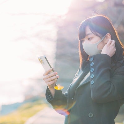 待ちぼうけでスマホを手に取る女性の写真