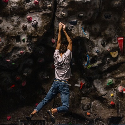 A climbing participant hangs by their hands on the climbing wall.