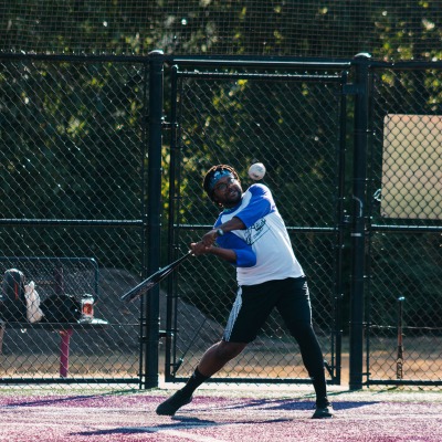 A softball participant swings at the ball as it approaches the bat.