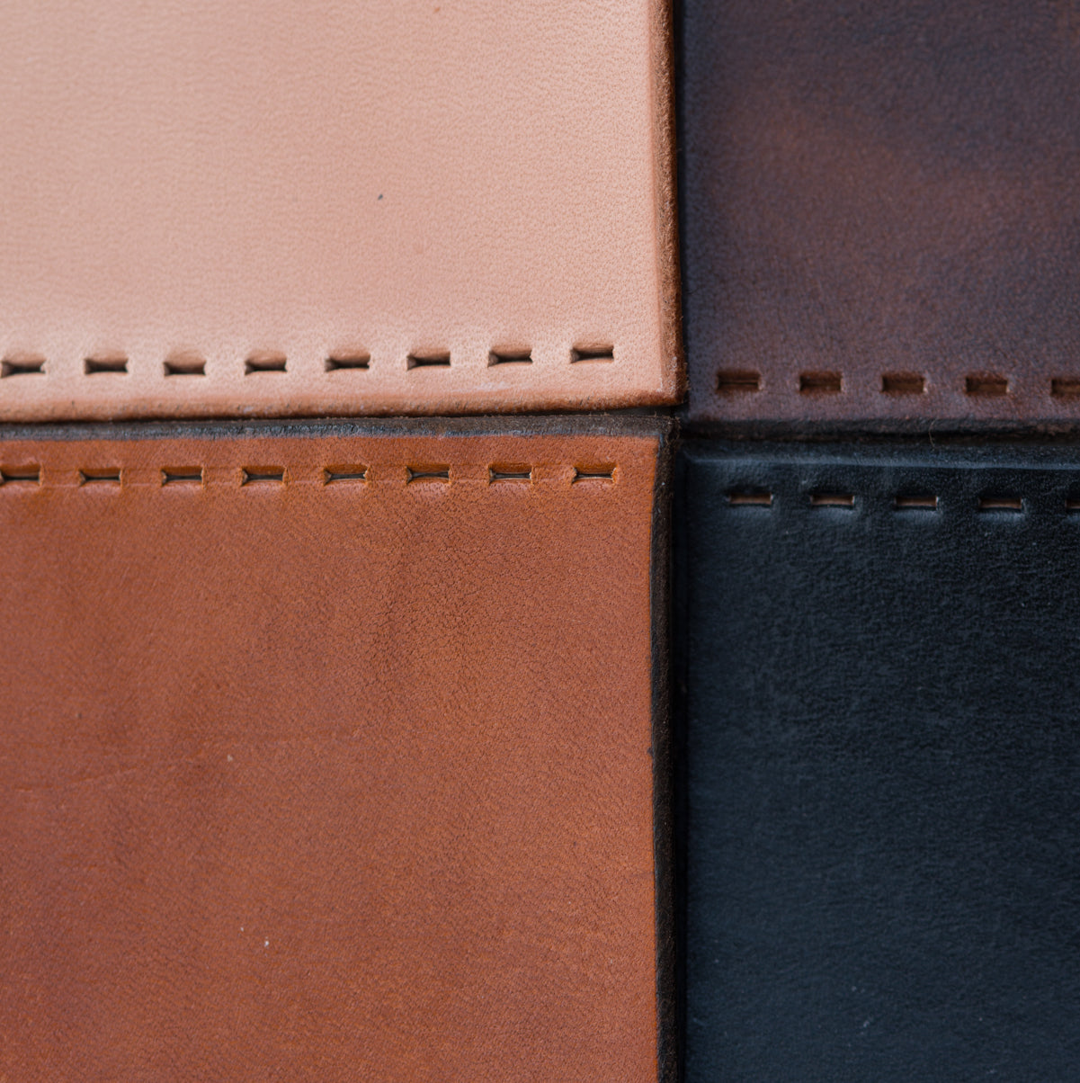 A close-up photo of Walnut Studiolo's leather, with four city grips in each of our four leather colors coming to meet in the center of the photo: Honey, Dark Brown, Black and Natural (Light Tan). Photography credit to Erin Berzel. 