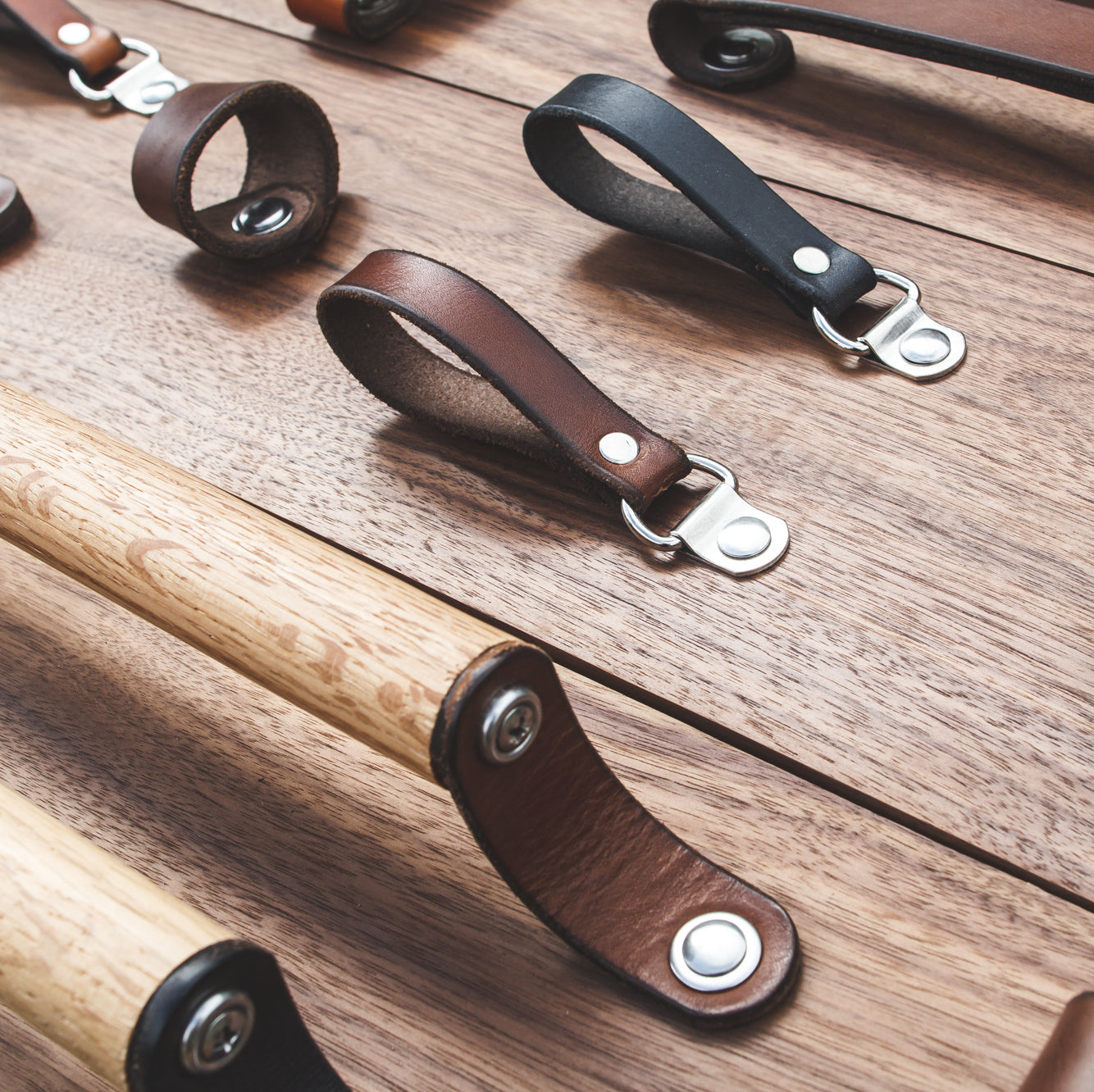 A variety of handcrafted leather and wood handles on a sample board as seen from above and an angle