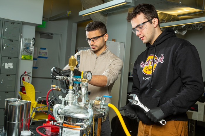 Aly Kombargi and Niko Tsakiris in a lab working on machinery