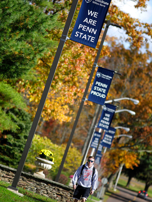 student walking across campus in fall foliage