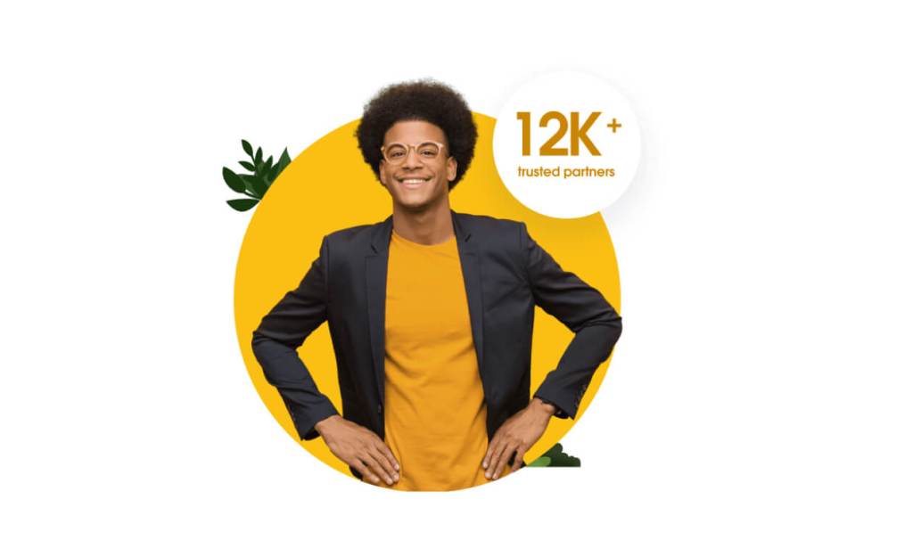 A smiling salesforce partner stands with a badge that reads 12K trusted partners