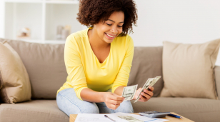 Woman sitting on sofa looking at spreadsheet and calculator