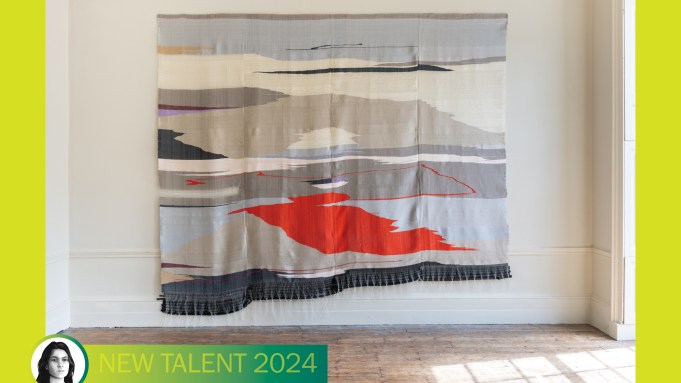 A textile with a landscapey abstraction hangs on a gallery wall.