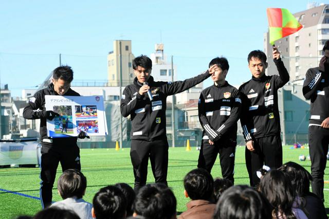 デフサッカーを学ぶイベントで、反則があった時に主審が旗で知らせることを子どもたちに教える選手たち=2024年12月14日、東京都江東区