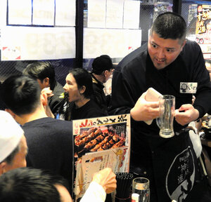 団体客でにぎわう居酒屋「三代目鳥メロ　新橋銀座口ガード下店」。店員（右）が対応に追われていた=東京都港区、宮崎健撮影