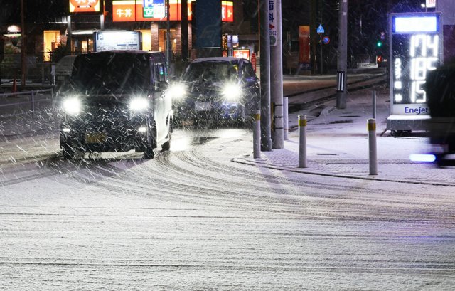 降り続く雪で白くなった道路を徐行して走る車=2025年1月10日午前6時9分、福岡市東区、小宮路勝撮影