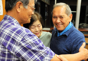 実父のいとこにあたる川畑幸治さんと、中原末子さんと抱き合うロブ・シプケンスさん（右）=2024年11月7日午後6時26分、鹿児島県大和村、大久保真紀撮影