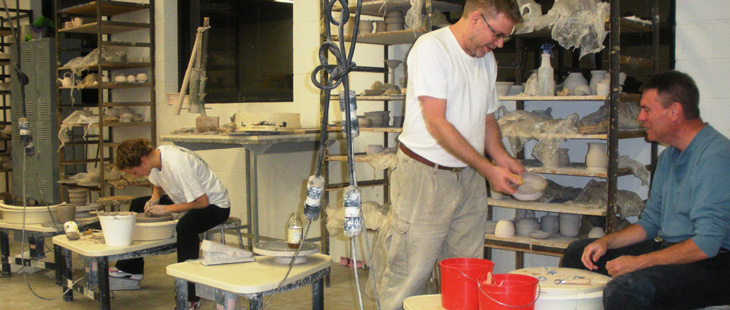 A student shows his instructor his pottery