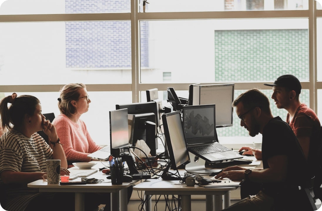 4 people working on computers in a pod