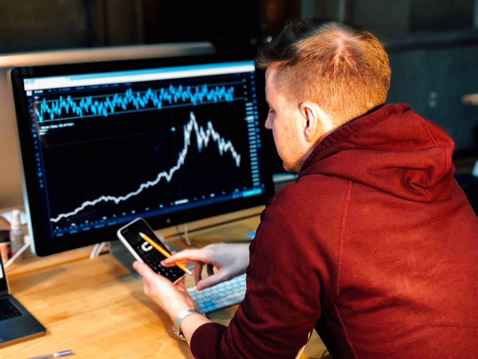 Person looking at charts on a computer and smartphone