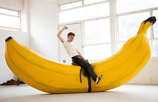 Jack Delaney, Fine Art student, sitting on a saddle strapped to a oversized banana